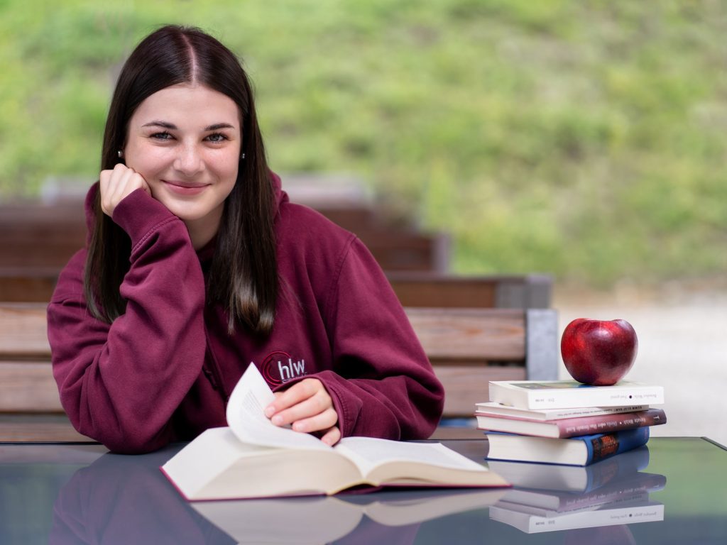 Schülerin lernt im Freien mit Büchern und Apfel vor sich